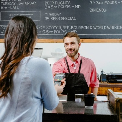 Cashier holding out the payment terminal for the customer who is inserting their card.