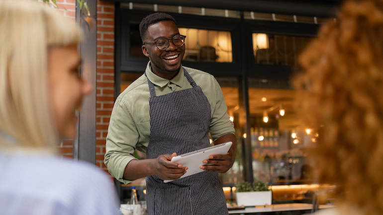 Server holding a tablet and taking orders from guests.