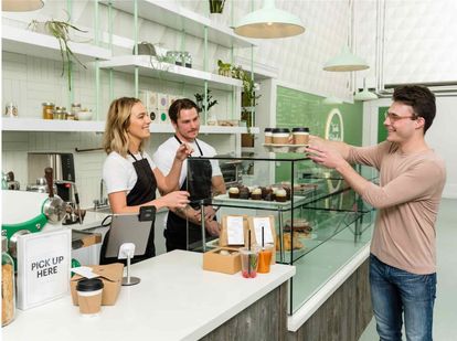 A coffee shop customer picking up a tray of coffees