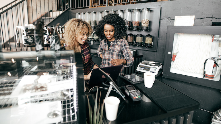 Two restaurant workers looking at a laptop.