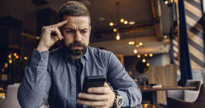 Man sitting looking at his phone upset.