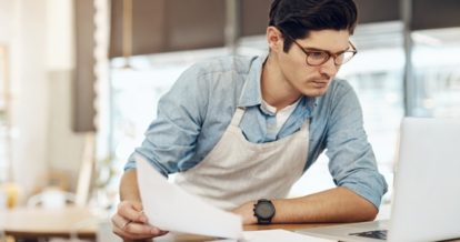 Restaurant employee looking at a laptop and papers