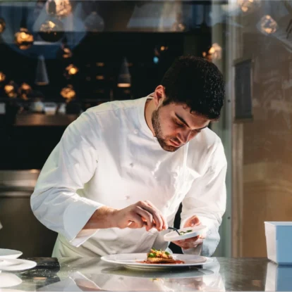 Chef in a restaurant kitchen preparing a plated dish