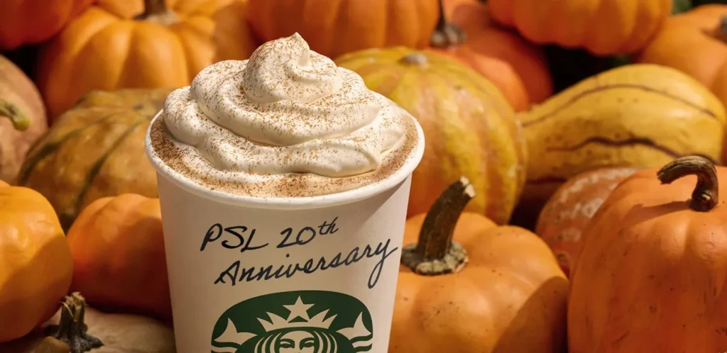 Starbucks pumpkin spice latte with orange pumpkins in the background.